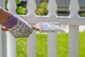 Woman painting a white picket fence